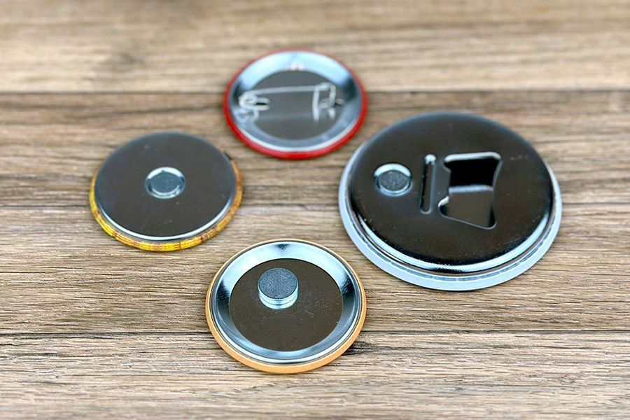 de verschillende mogelijkheden achteraan de buttons: speld, koelkastmagneet, kledingmagneet of flesopener